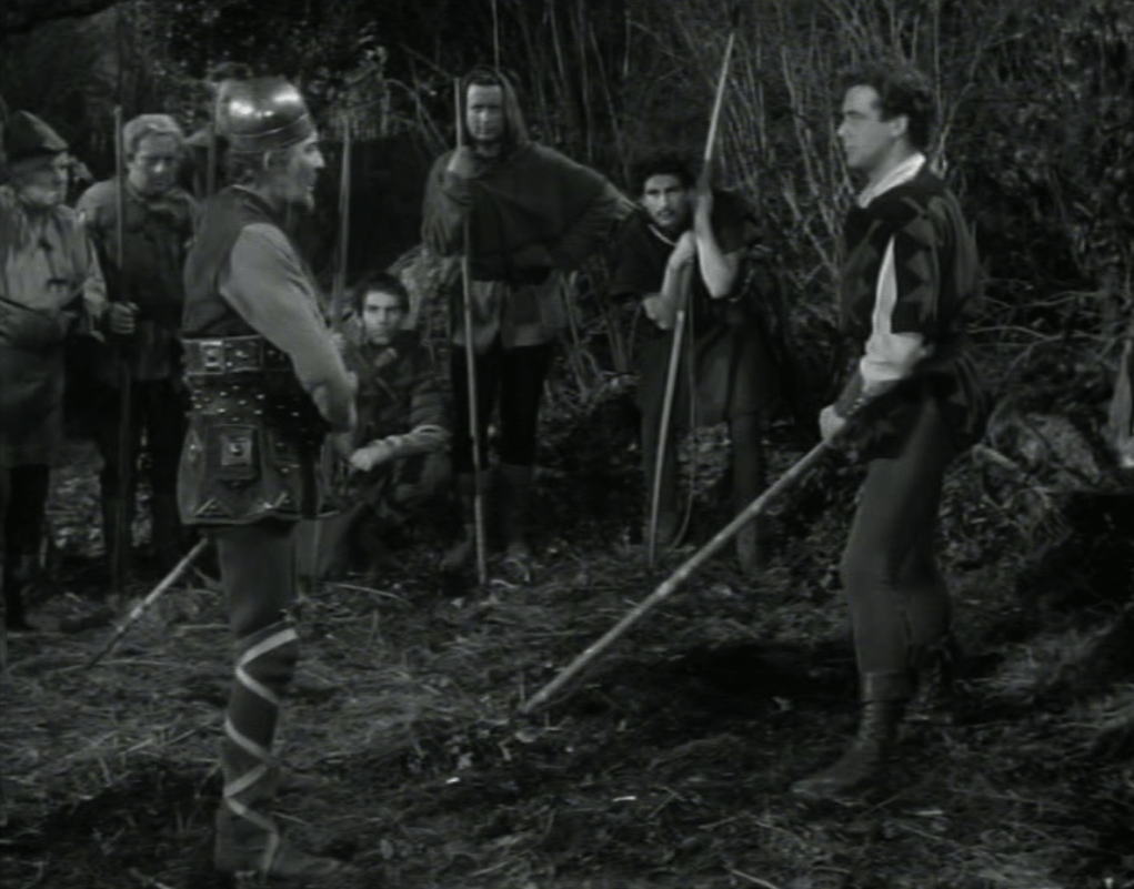 The outlaws watch as Will challenges Robin to a quarterstaff duel
